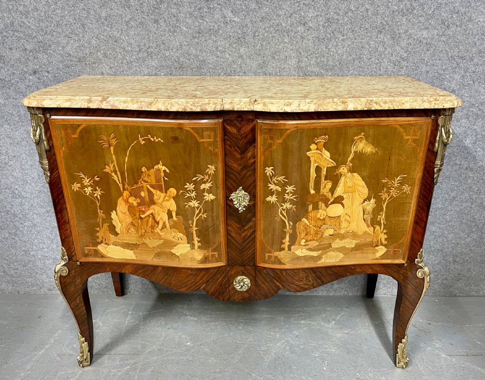 A French Chinoiserie marquetry commode featuring curved doors with inlaid pictorial scenes, a marble top, and gilt bronze mounts on cabriole legs.