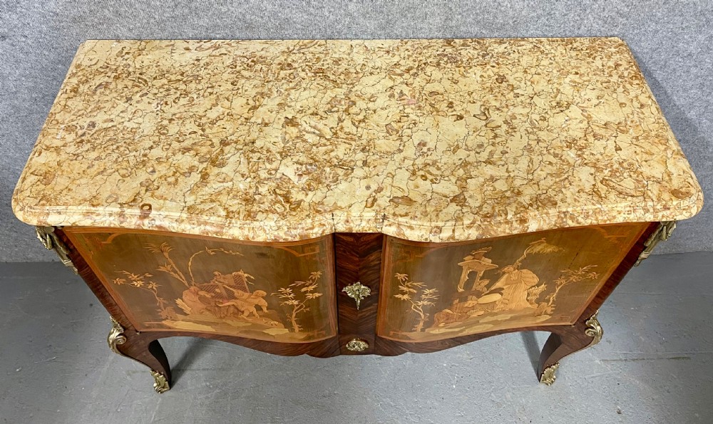 A French Chinoiserie marquetry commode featuring curved doors with inlaid pictorial scenes, a marble top, and gilt bronze mounts on cabriole legs. View II