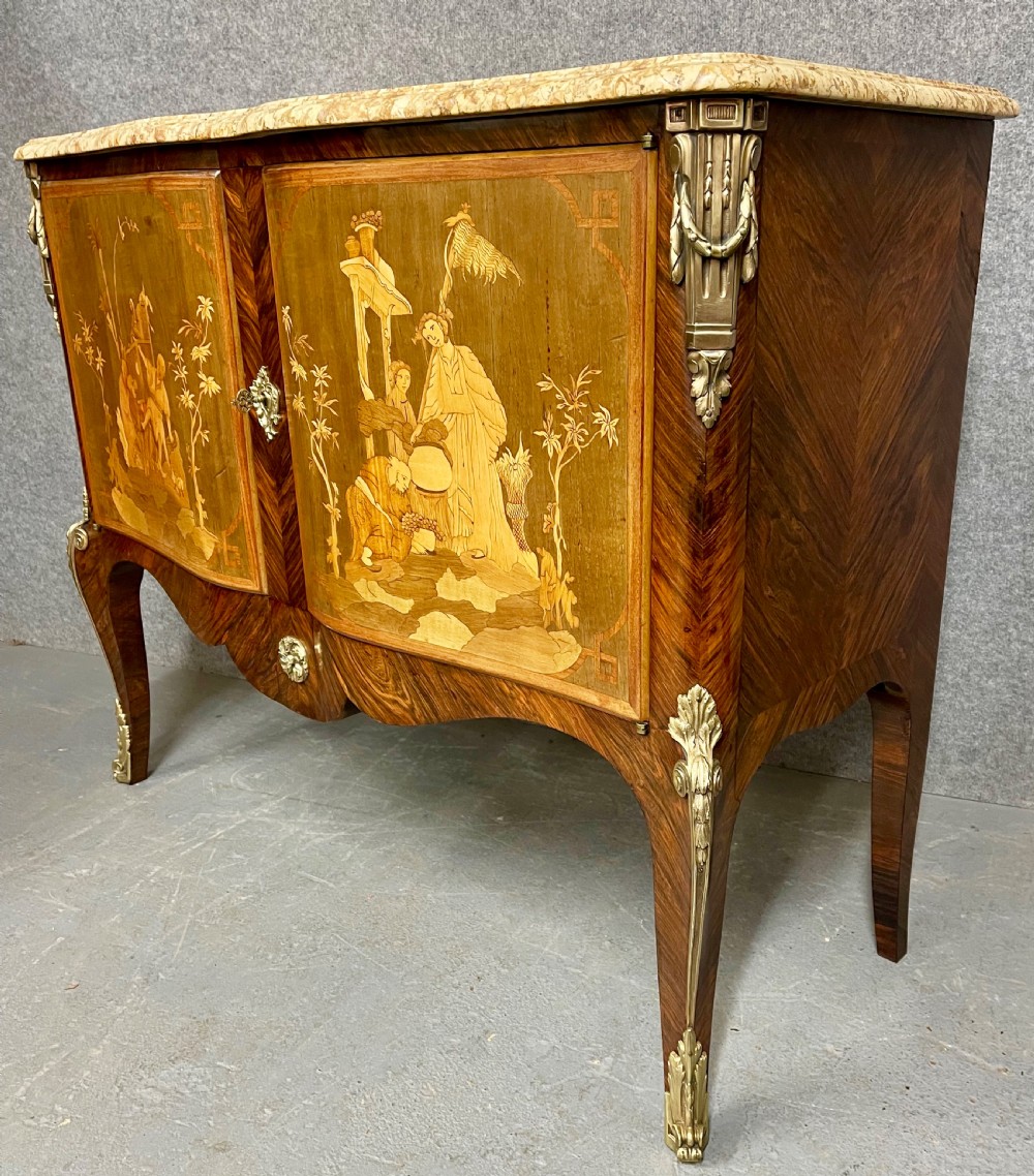 A French Chinoiserie marquetry commode featuring curved doors with inlaid pictorial scenes, a marble top, and gilt bronze mounts on cabriole legs. View V