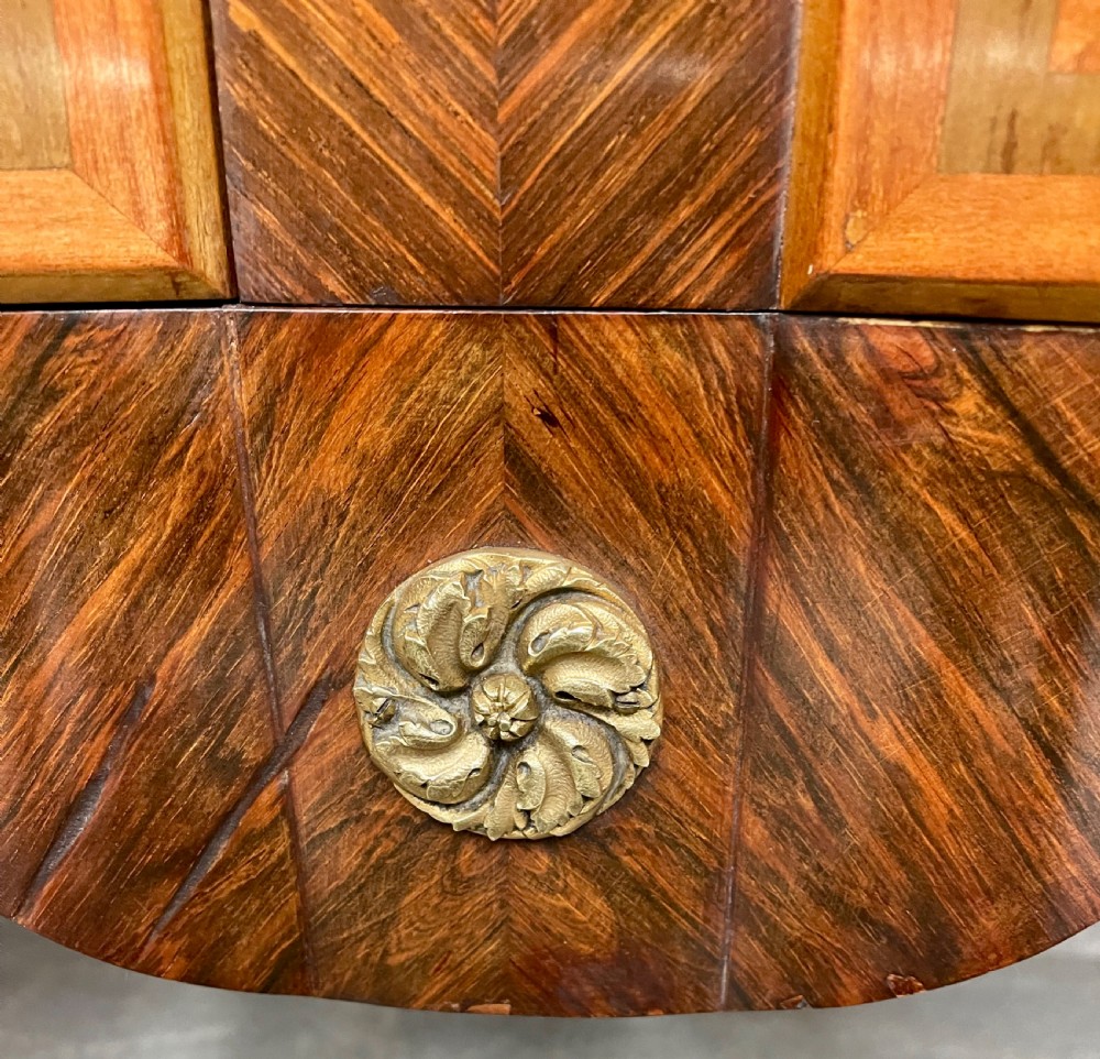A French Chinoiserie marquetry commode featuring curved doors with inlaid pictorial scenes, a marble top, and gilt bronze mounts on cabriole legs. View VIII