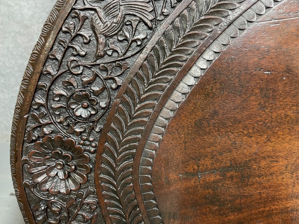 An oval Anglo-Indian dark wood centre table featuring an intricately carved floral border, a central radiating oval medallion, and legs sculpted as elephant heads with white tusks. View IV