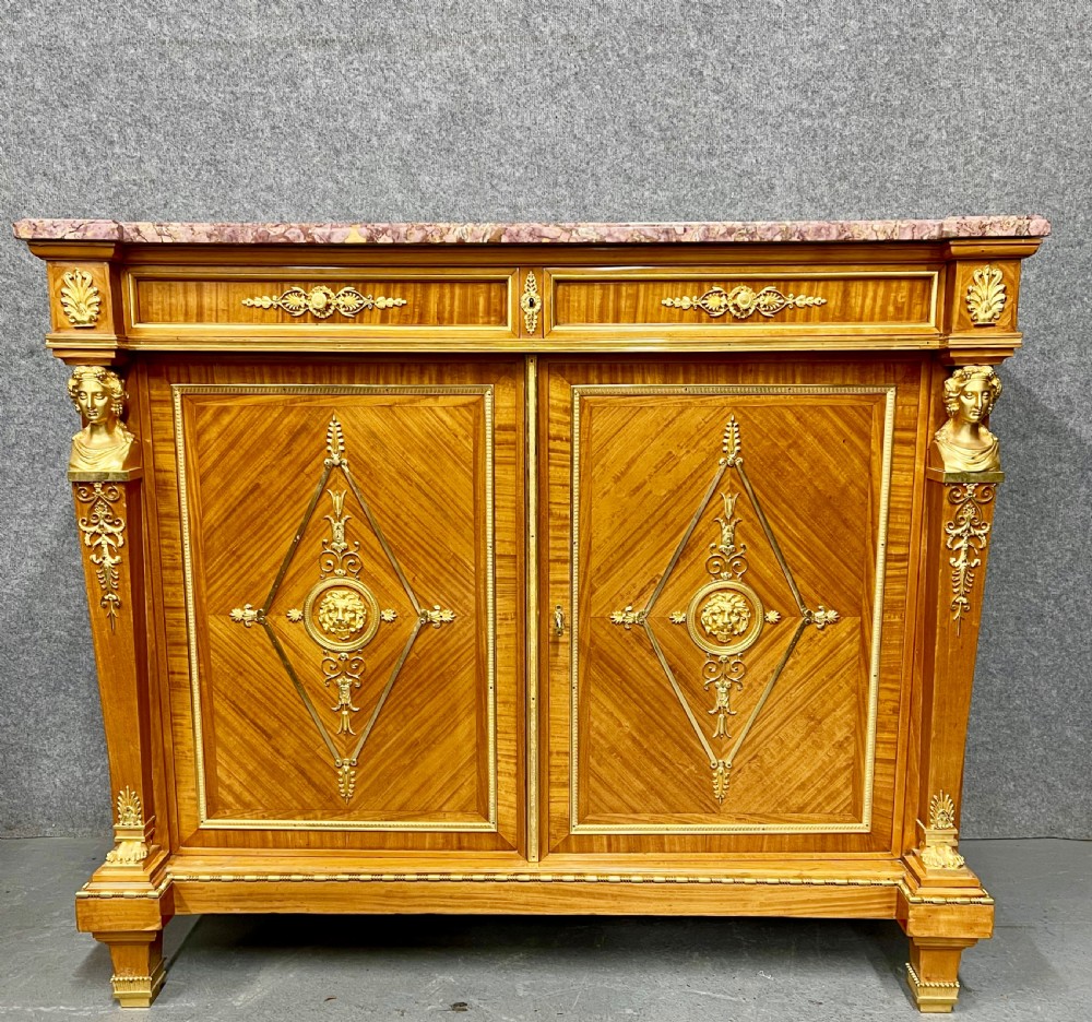 A pair of French Neoclassical side cabinets featuring satinwood parquetry, intricate gilt-bronze mounts, corner bust sculptures, and pink marble tops. View III