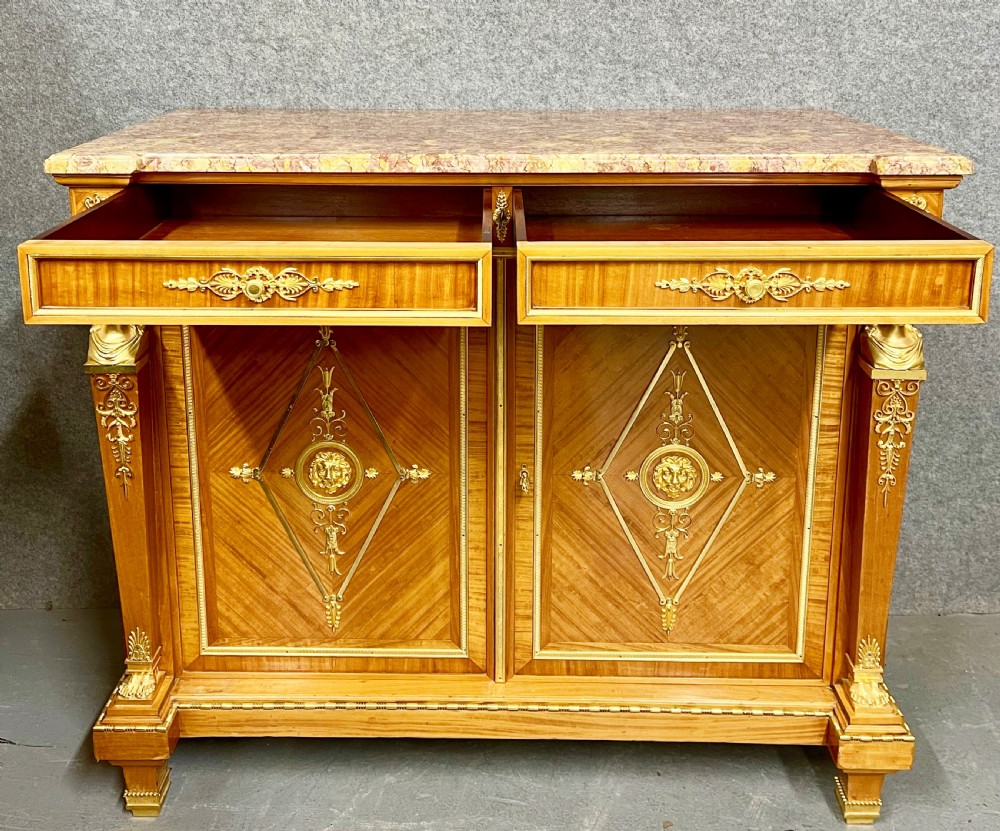 A pair of French Neoclassical side cabinets featuring satinwood parquetry, intricate gilt-bronze mounts, corner bust sculptures, and pink marble tops. View IX