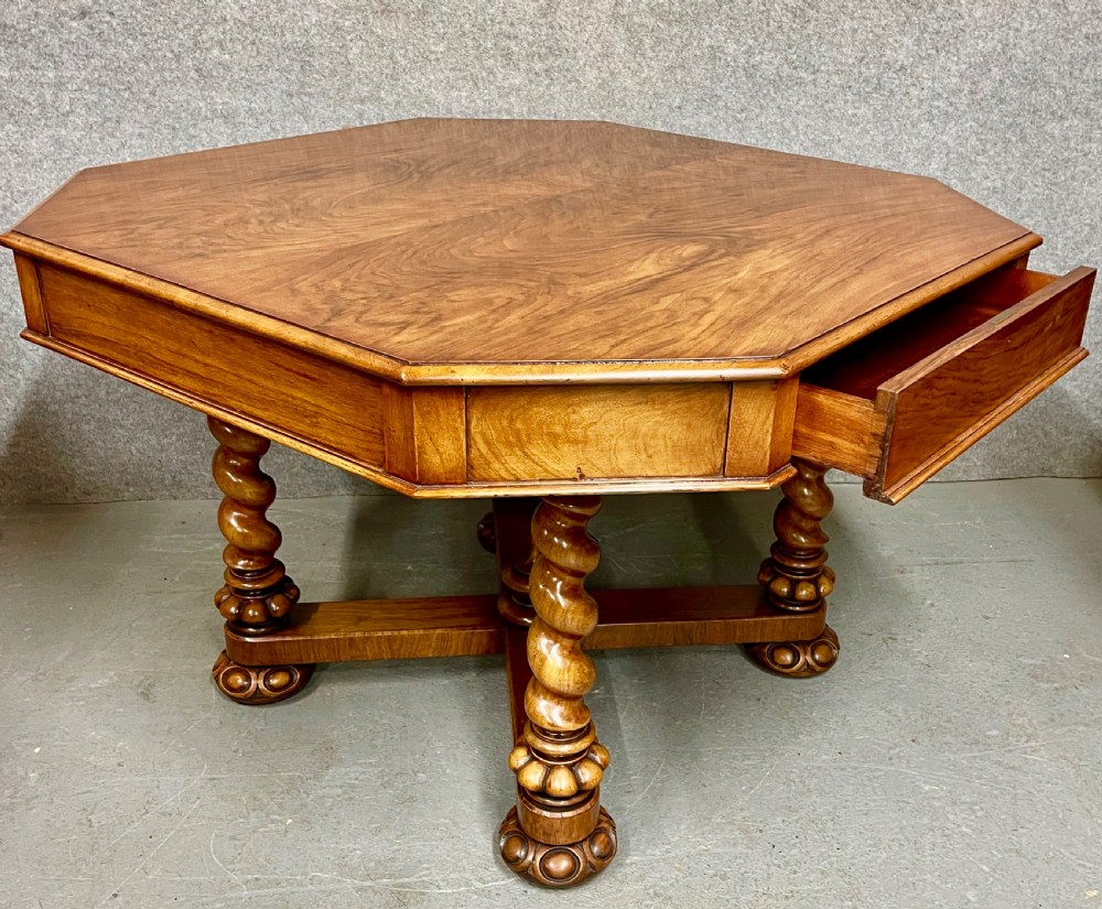A Victorian octagonal walnut library table featuring spiral barley twist legs, a cross stretcher with a central finial, and open pull-out drawers. View V