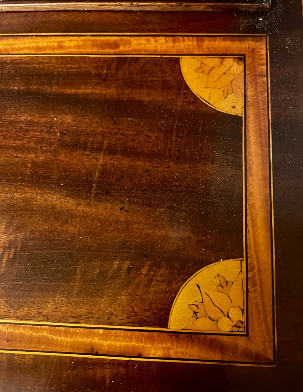 A Sheraton Revival mahogany cabinet featuring a swan-neck pediment, glazed upper doors with geometric bars, inlaid satinwood stringing, and multiple drawers set on tapered square legs. View V