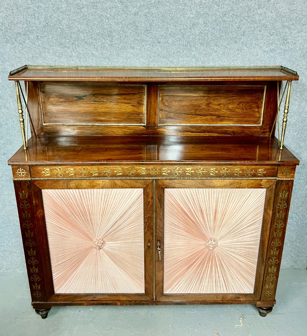 A Regency rosewood chiffonier featuring ornate brass marquetry inlay, twin doors with pleated fabric panels, and a raised top shelf supported by brass columns. View II