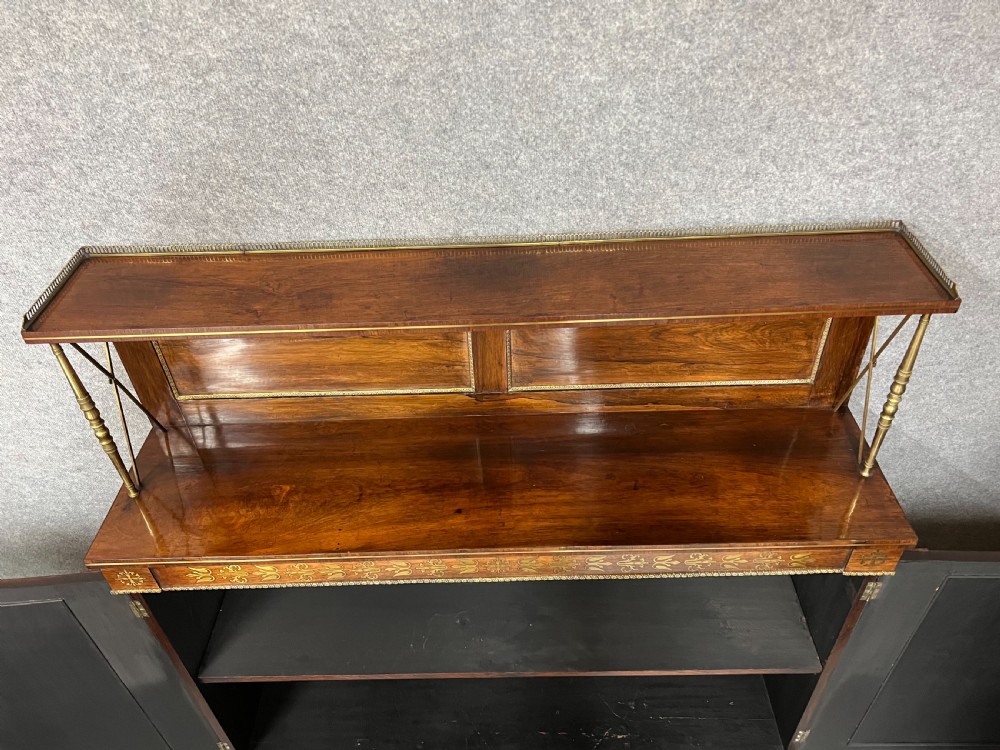 A Regency rosewood chiffonier featuring ornate brass marquetry inlay, twin doors with pleated fabric panels, and a raised top shelf supported by brass columns. View VII
