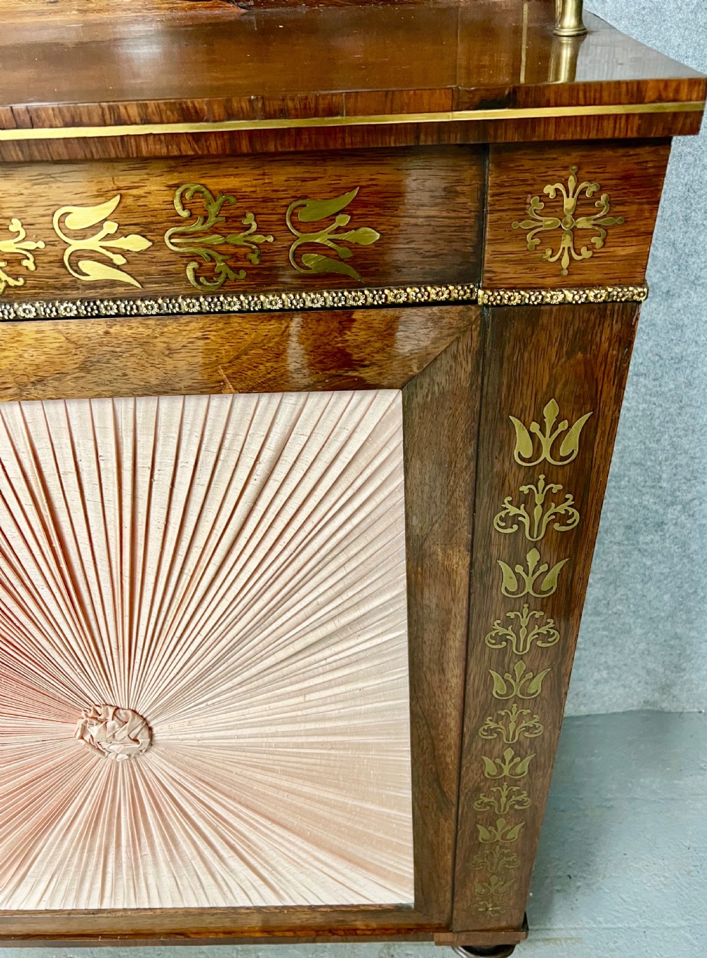 A Regency rosewood chiffonier featuring ornate brass marquetry inlay, twin doors with pleated fabric panels, and a raised top shelf supported by brass columns. View XI