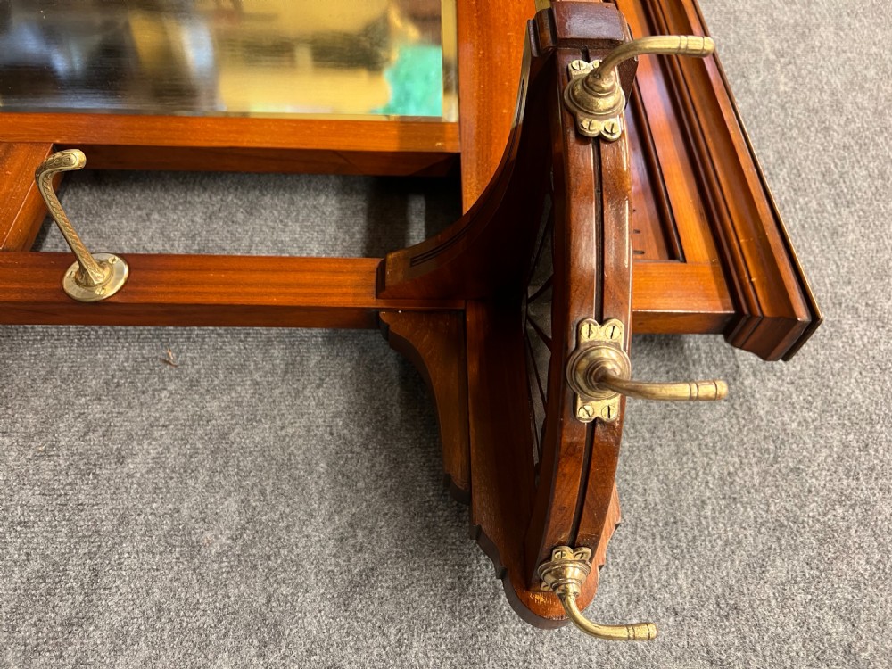 A late 19th-century mahogany hall stand featuring a central mirror, brass hooks, inlaid Minton ceramic tiles, and two matching side chairs. View XVI
