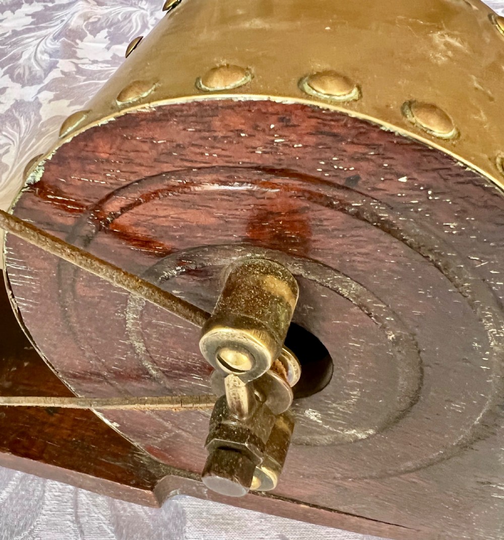 An antique mechanical rotary hearth bellows constructed from dark mahogany with a brass-trimmed cylinder housing, brass nozzle, and hand-crank pulley wheel. View III