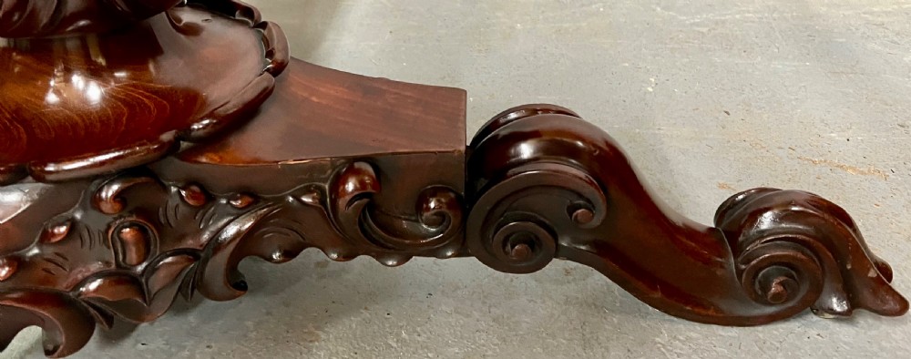 A circular Victorian mahogany tilt-top centre table displaying highly figured flame mahogany veneer on a carved tripod pedestal base. View IX