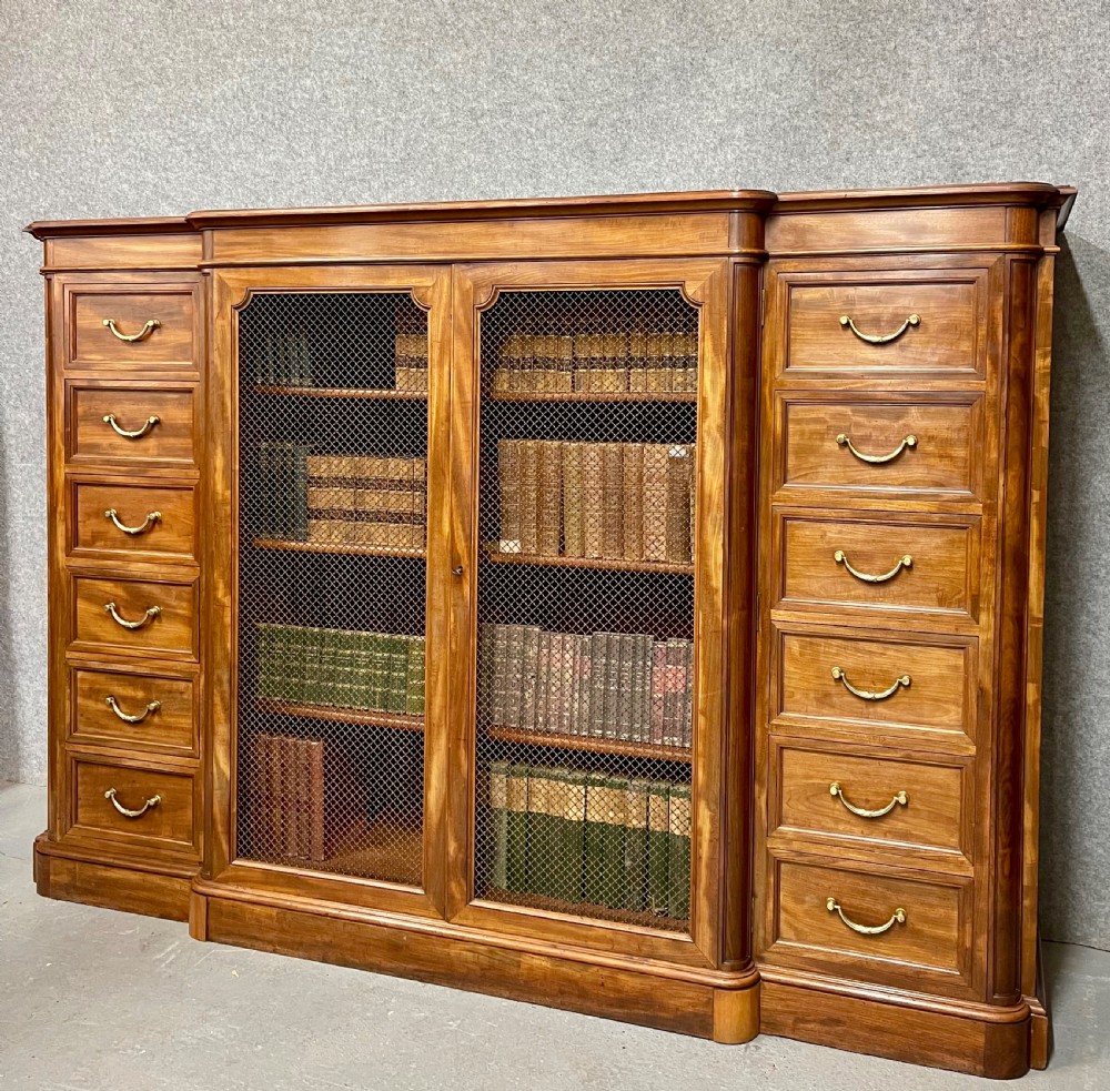A large antique wooden breakfront library bookcase with twin central wire mesh doors flanked by stacks of six drawers on each side. View II