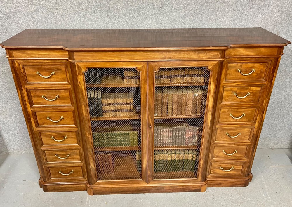 A large antique wooden breakfront library bookcase with twin central wire mesh doors flanked by stacks of six drawers on each side. View III
