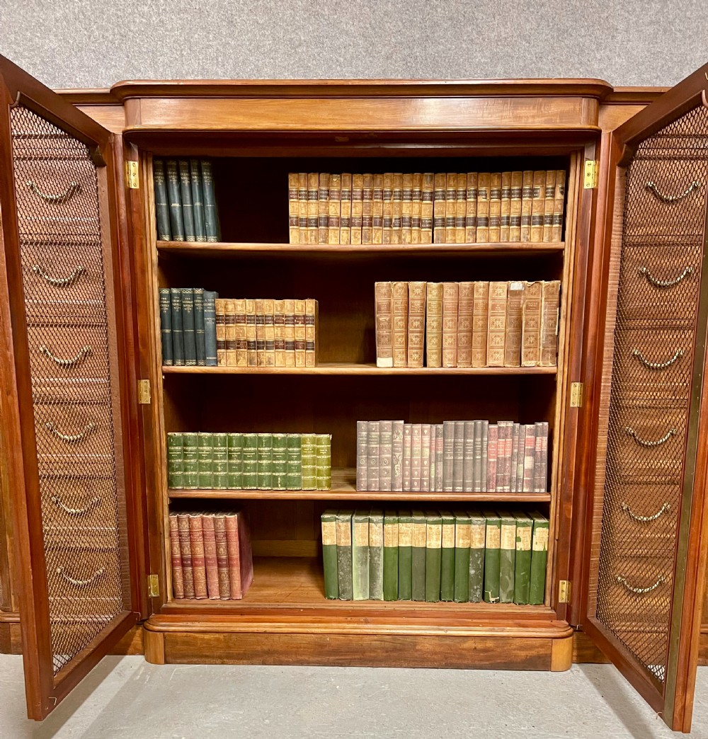 A large antique wooden breakfront library bookcase with twin central wire mesh doors flanked by stacks of six drawers on each side. View X
