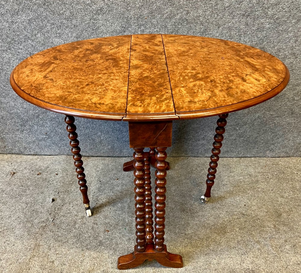 A compact Victorian drop-leaf Sutherland table featuring highly figured burr walnut veneer tabletop, bobbin-turned legs, and ceramic castors. View II