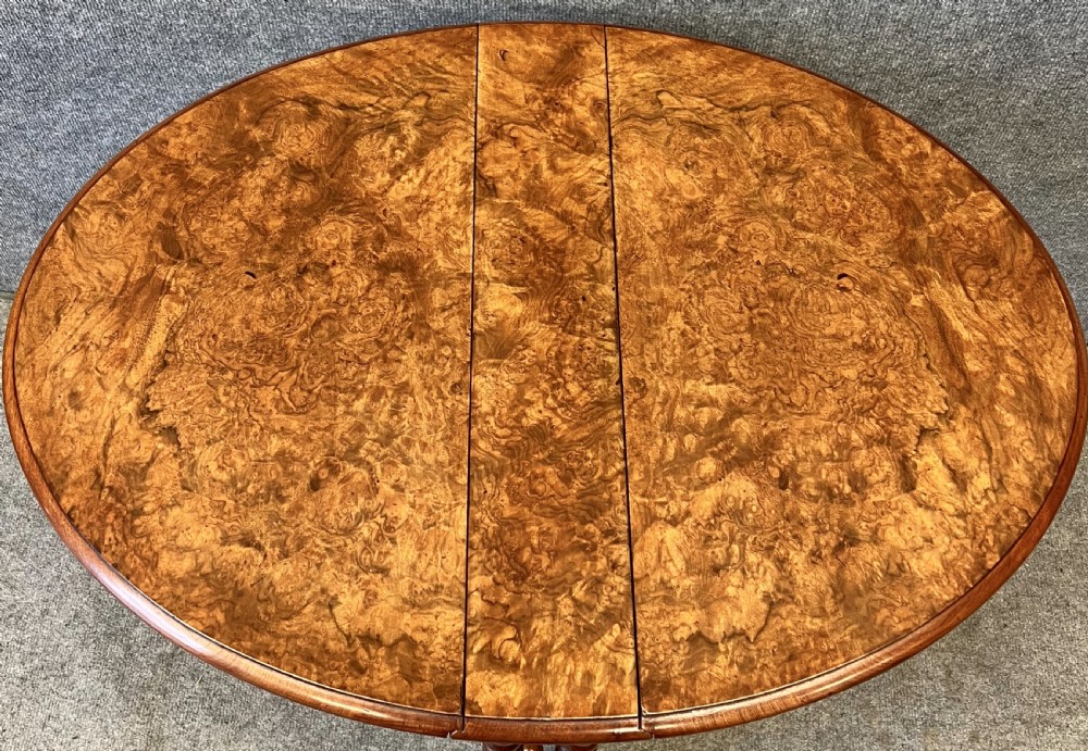 A compact Victorian drop-leaf Sutherland table featuring highly figured burr walnut veneer tabletop, bobbin-turned legs, and ceramic castors. View III