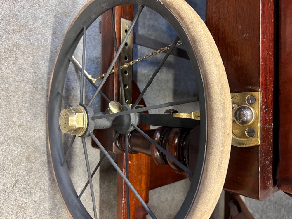 A Victorian mechanical reclining invalid armchair featuring buttoned tan leather upholstery, brass nailhead trim, a mahogany frame, and spoked side wheels. View VIII