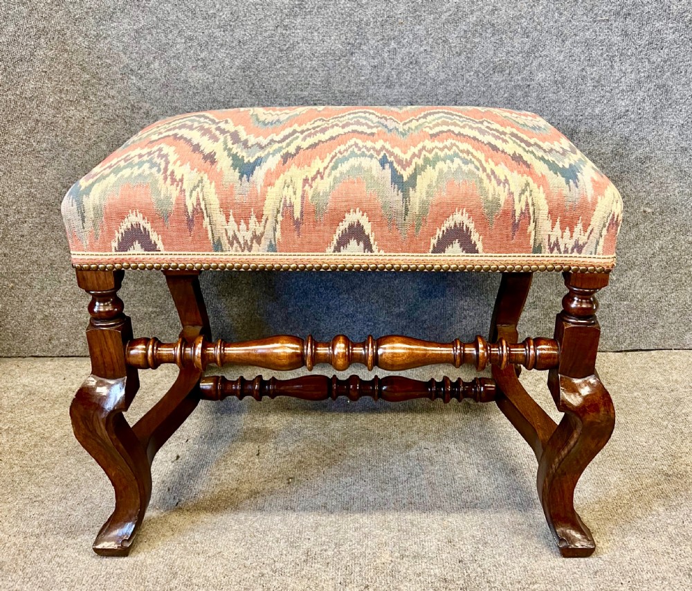 A pair of 18th-century style walnut stools featuring turned stretchers, curved legs, and patterned flame-stitch upholstery finished with brass studs. View II