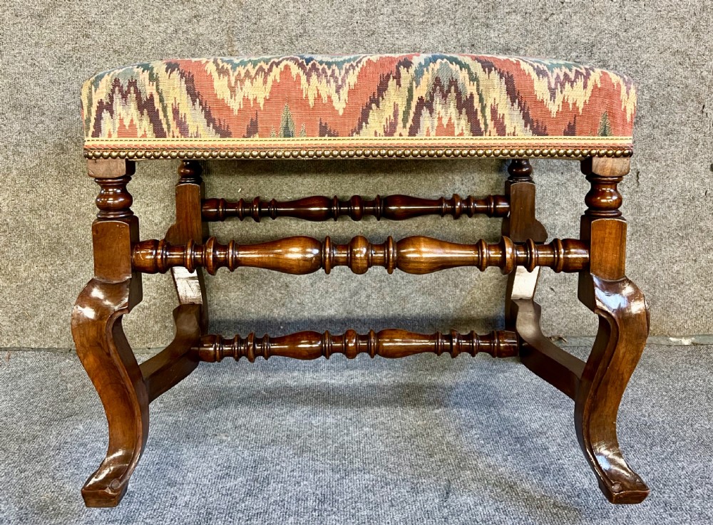 A pair of 18th-century style walnut stools featuring turned stretchers, curved legs, and patterned flame-stitch upholstery finished with brass studs. View III