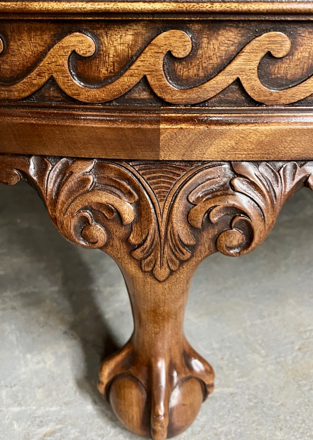 A semi-circular Chippendale style mahogany demi-lune side cabinet featuring flame mahogany veneers, a carved border, a central oval door panel, and carved claw and ball feet. View V