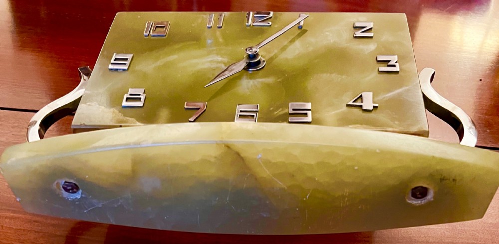 An Art Deco green onyx clock with stylized chrome numerals and hands supported on a serpentine chrome frame and stone base. View II