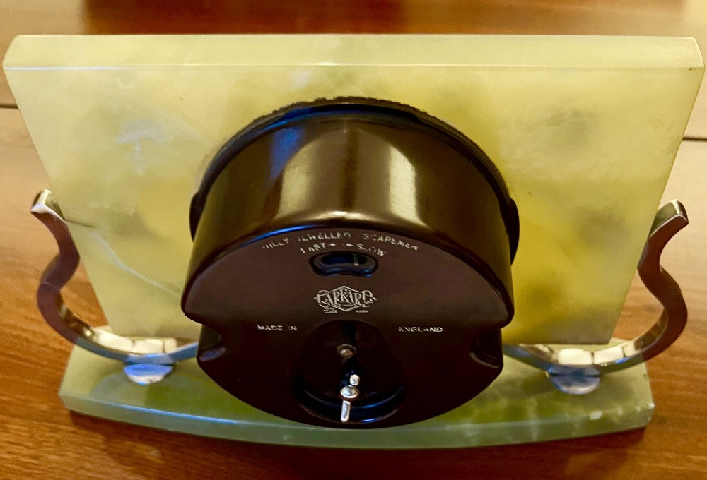 An Art Deco green onyx clock with stylized chrome numerals and hands supported on a serpentine chrome frame and stone base. View V