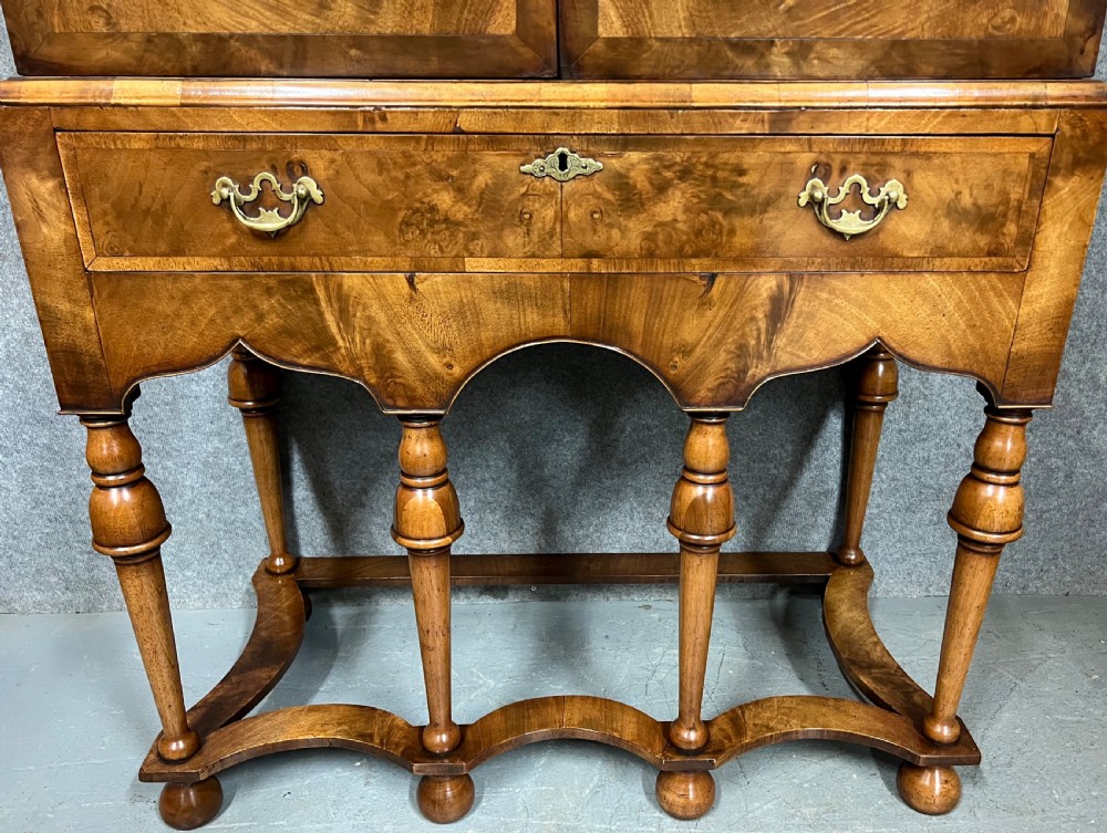 A William and Mary style burr walnut cocktail cabinet on stand featuring engraved brass strap hinges, double doors, a single drawer, turned legs, and a shaped stretcher. View IX