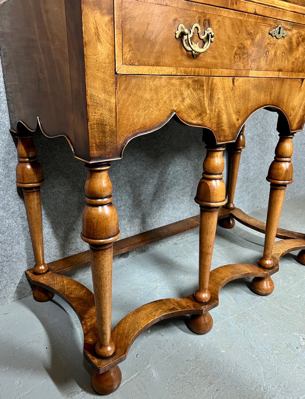 A William and Mary style burr walnut cocktail cabinet on stand featuring engraved brass strap hinges, double doors, a single drawer, turned legs, and a shaped stretcher. View X