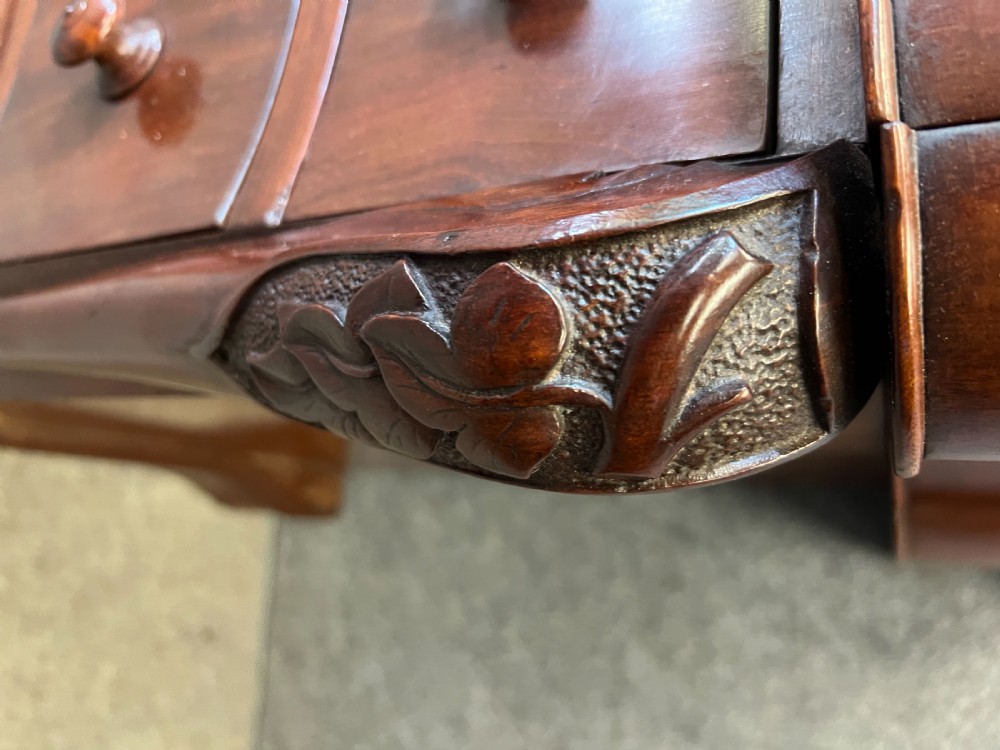 A Victorian figured mahogany pedestal desk featuring a shaped gilded leather surface, serpentine drawer fronts, and turned wooden knobs. View X