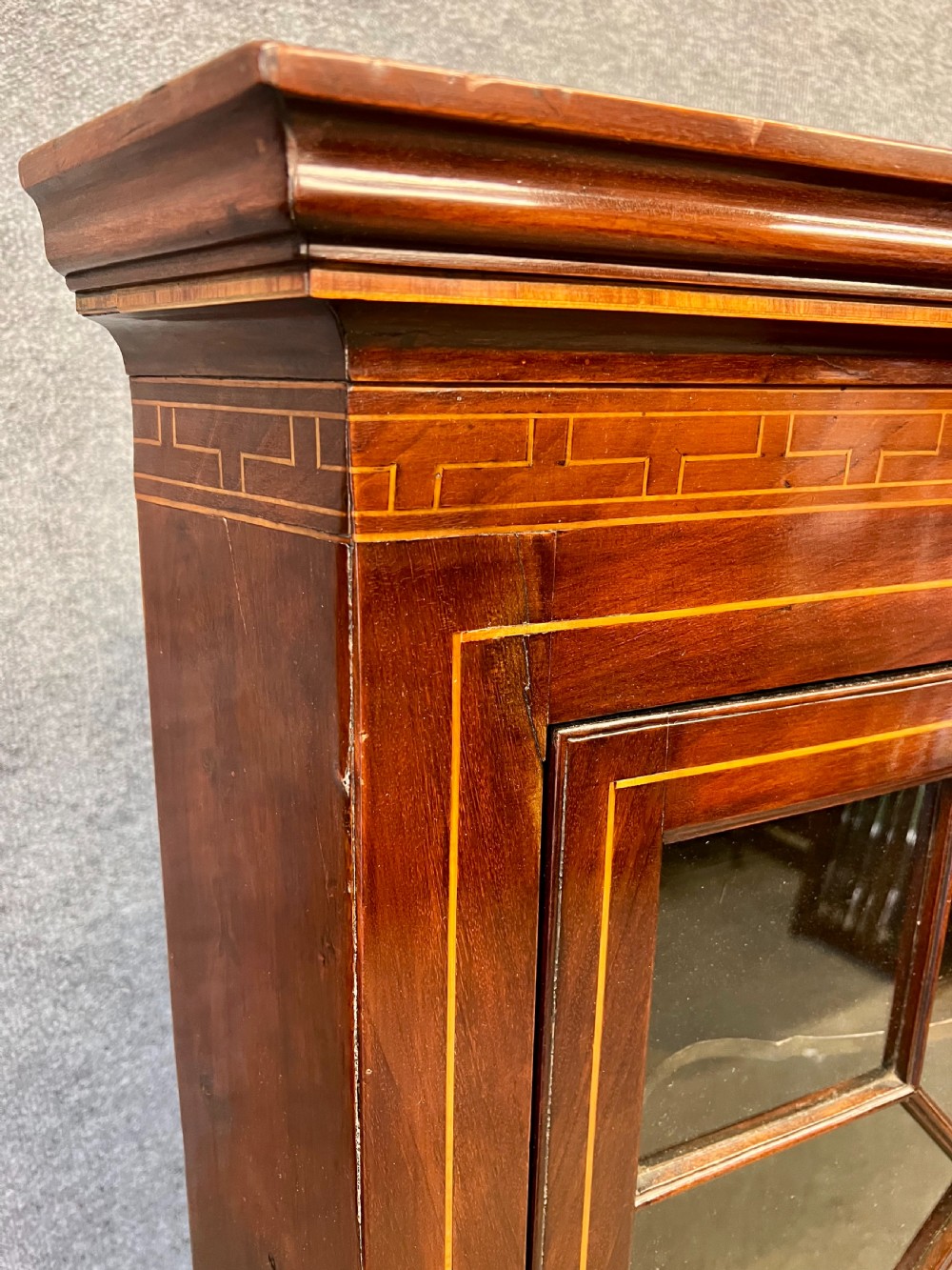 A George III hanging corner cupboard made of dark mahogany, featuring an astragal glazed door and decorative geometric inlay along the upper frieze. View III