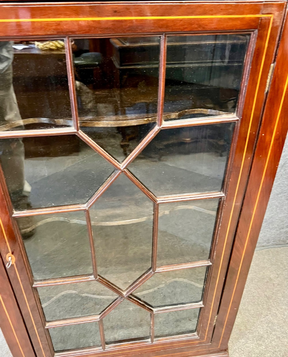 A George III hanging corner cupboard made of dark mahogany, featuring an astragal glazed door and decorative geometric inlay along the upper frieze. View IV