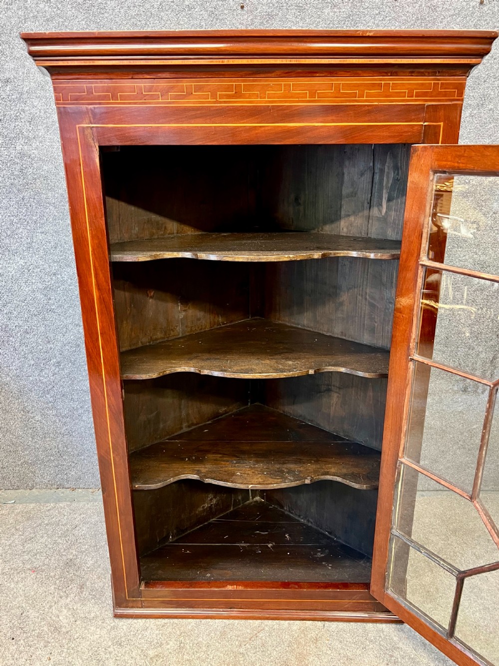 A George III hanging corner cupboard made of dark mahogany, featuring an astragal glazed door and decorative geometric inlay along the upper frieze. View VII