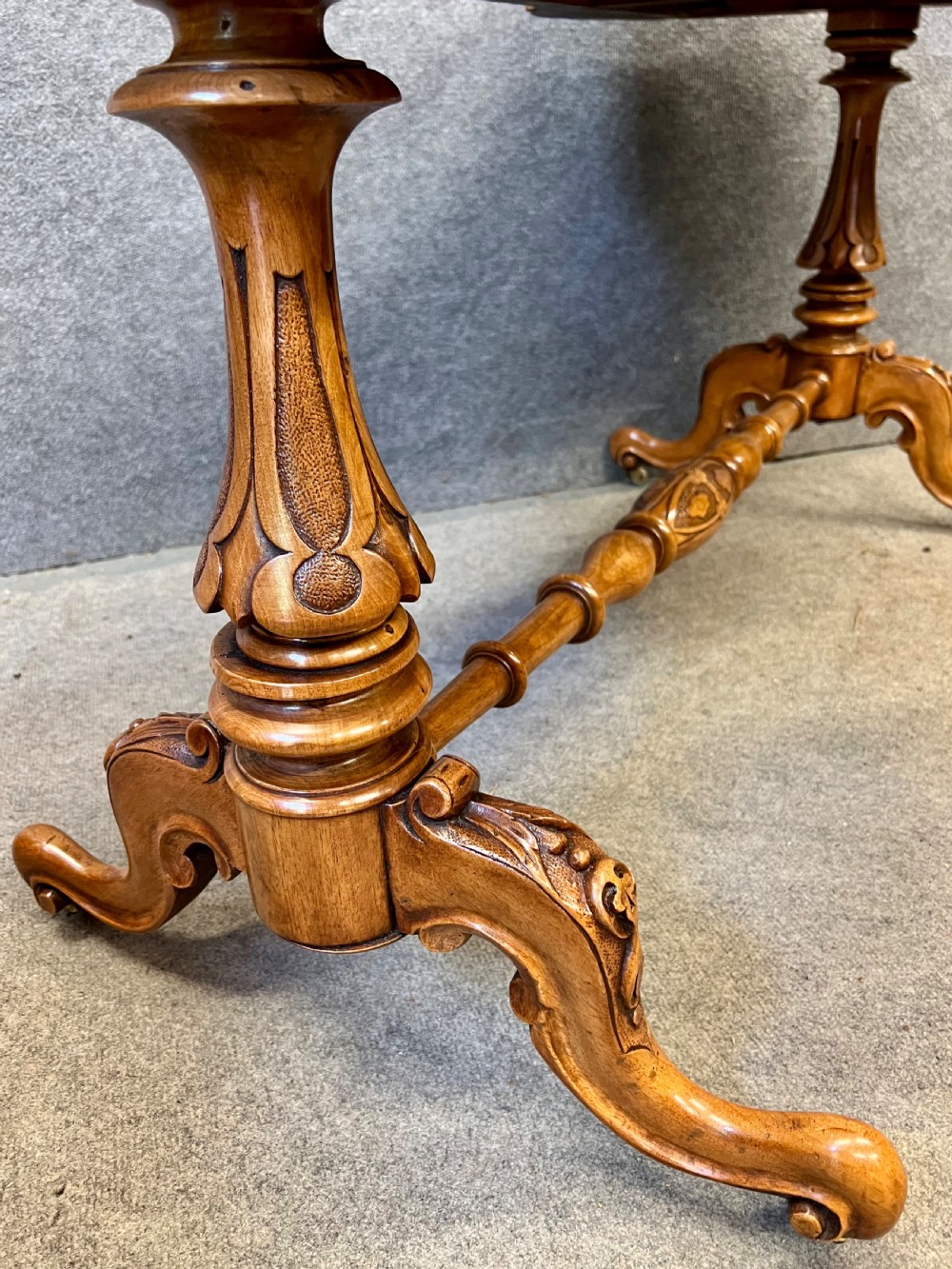 A Victorian burr walnut kidney-shaped writing desk featuring a burgundy leather writing surface, openwork carved frieze, turned central stretcher, and cabriole legs on brass castors. View VIII