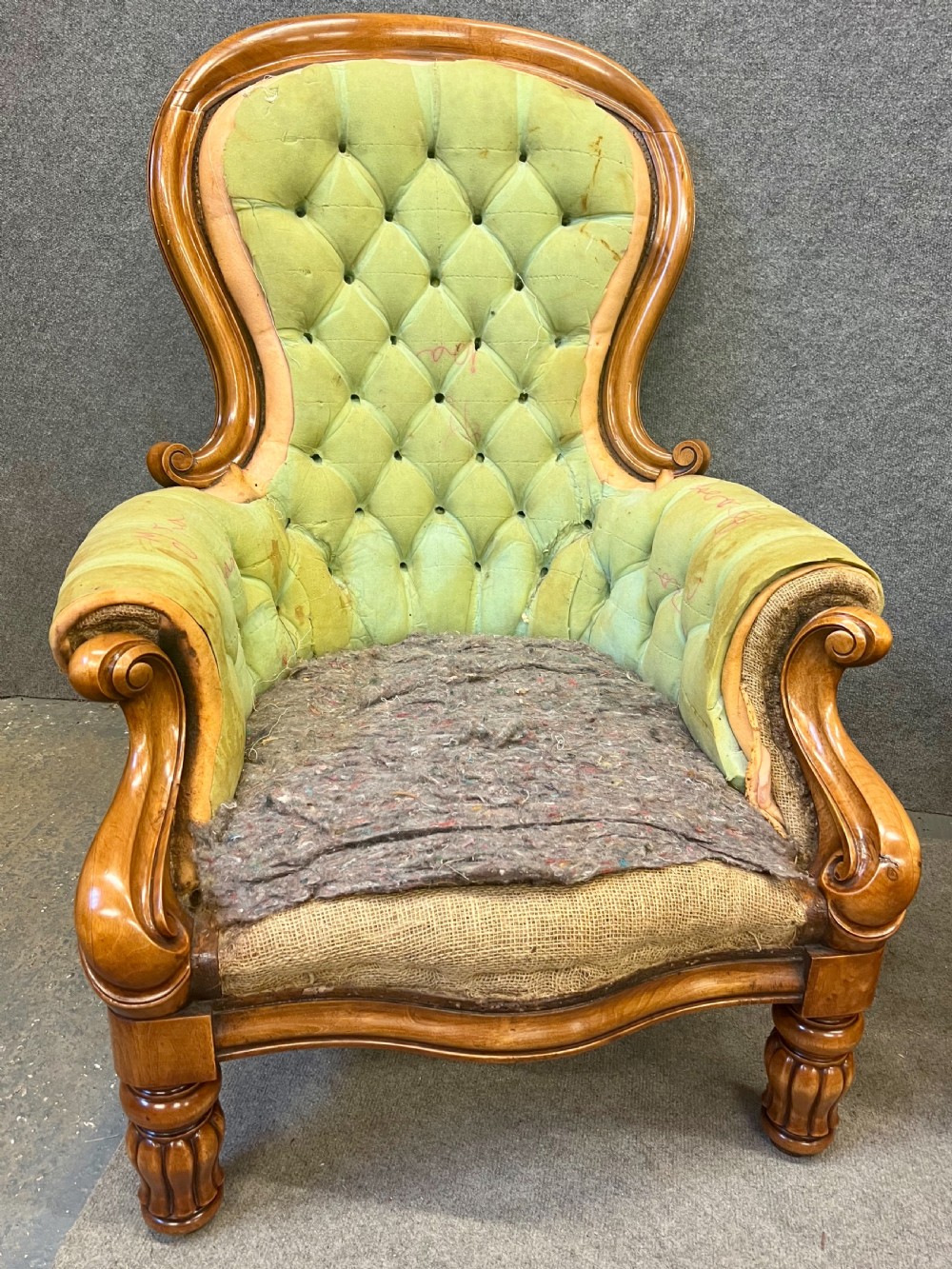 A pair of 1930s Victorian revival walnut armchairs featuring carved show-wood frames, button-back tufting, and worn green upholstery awaiting restoration. View II