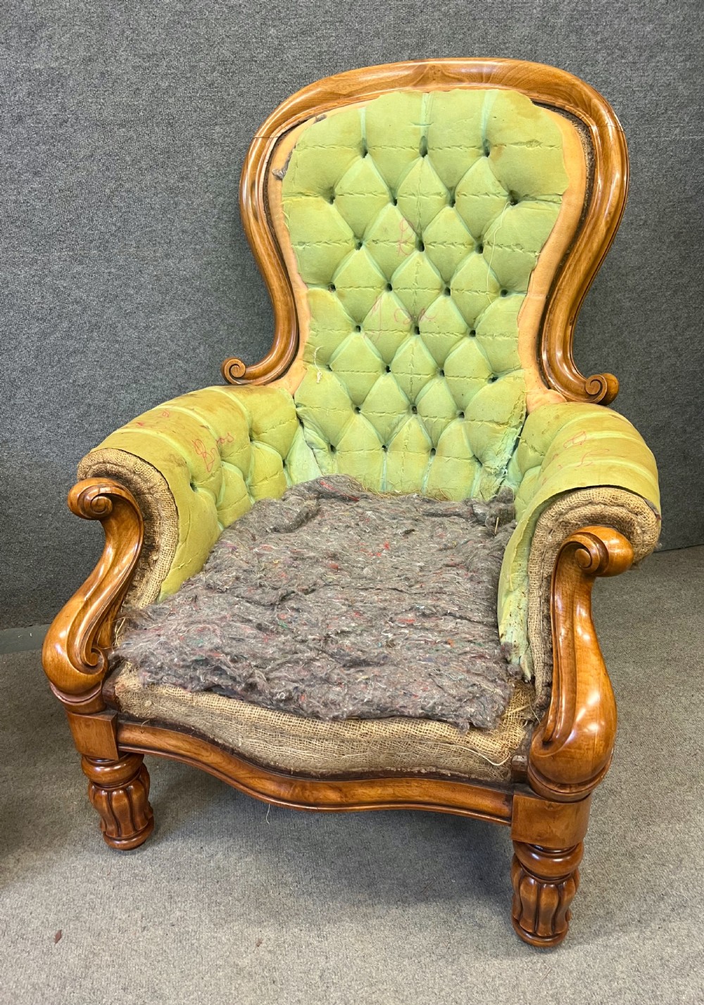 A pair of 1930s Victorian revival walnut armchairs featuring carved show-wood frames, button-back tufting, and worn green upholstery awaiting restoration. View III