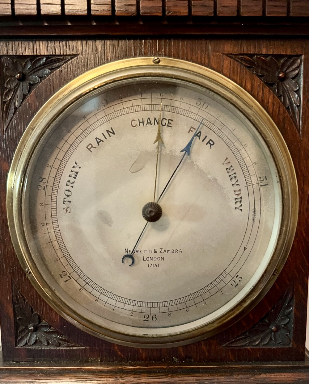 A Victorian carved dark oak wall barometer featuring an upper mercury thermometer flanked by fluted columns and a lower circular brass-rimmed aneroid dial. View II