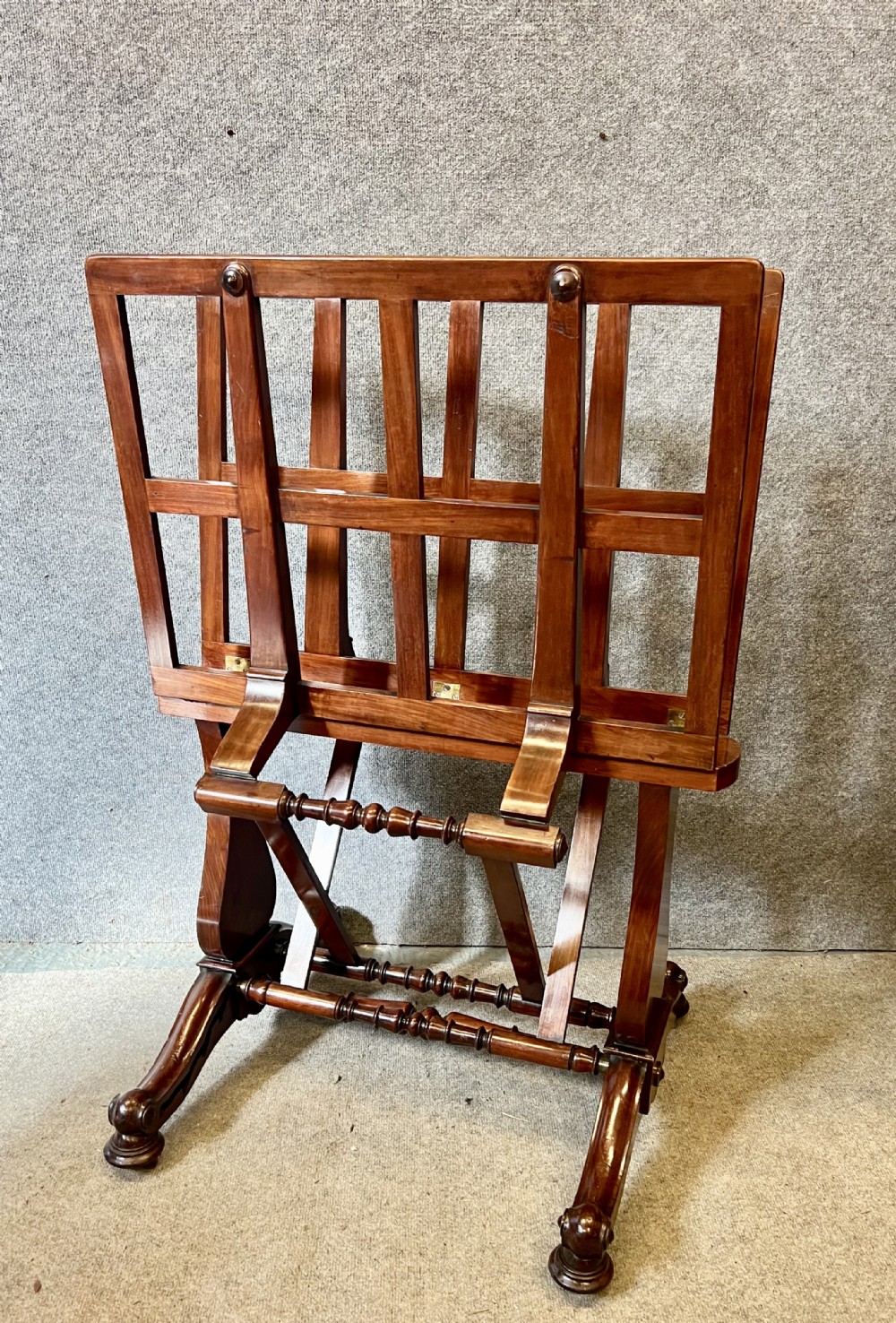 A George IV mahogany folio stand with hinged slatted frames, turned stretchers, and carved scrolled feet.