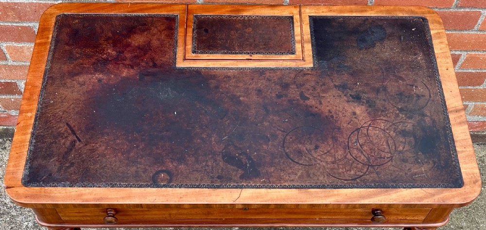 A Regency mahogany chamber writing table featuring a leather-inset surface, single long drawer, turned wooden knobs, and reeded legs on brass castors. View VII