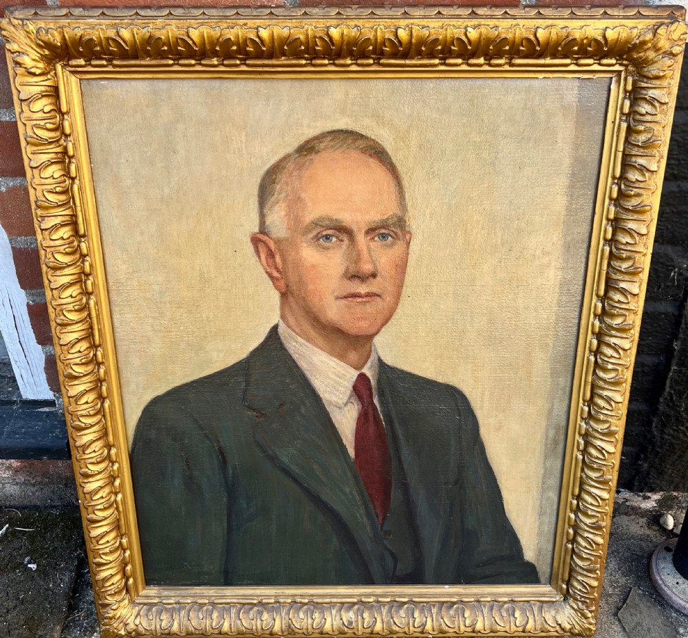 An oil painting on canvas depicting a gentleman in a suit and tie, set within a carved gold gilt frame.