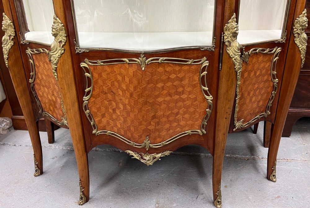 An antique French Louis XV style vitrine cabinet featuring a serpentine glass front, gilded ormolu mounts, parquetry lower panels, and cabriole legs. View VI