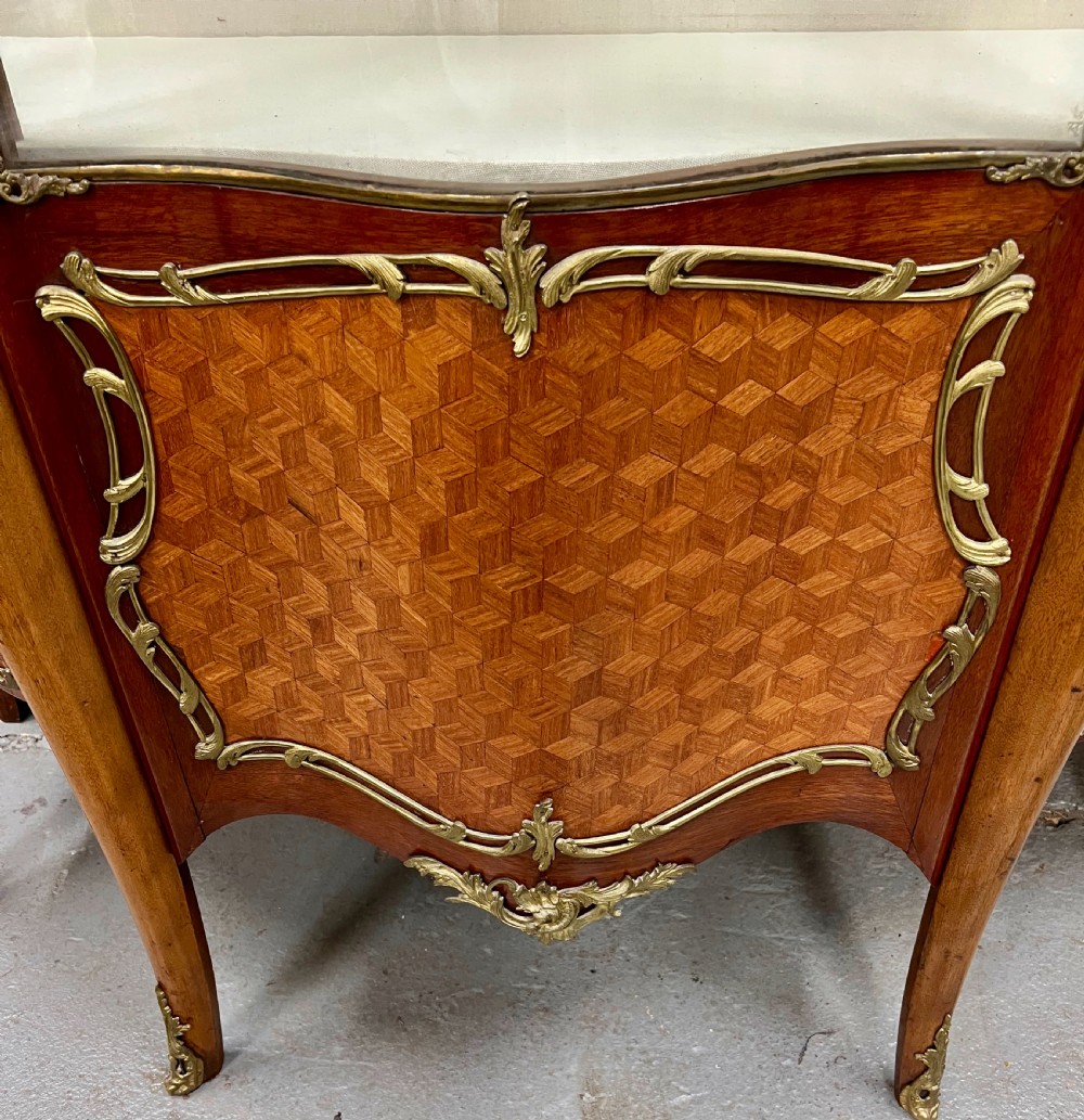An antique French Louis XV style vitrine cabinet featuring a serpentine glass front, gilded ormolu mounts, parquetry lower panels, and cabriole legs. View IX