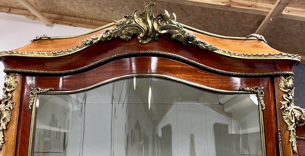 An antique French Louis XV style vitrine cabinet featuring a serpentine glass front, gilded ormolu mounts, parquetry lower panels, and cabriole legs. View XI