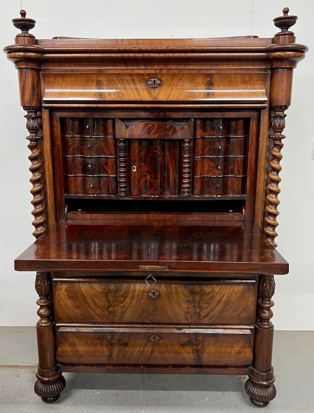 A 19th-century Biedermeier flame mahogany secretaire desk featuring spiralled barley twist columns, a fall-front writing surface, and a fitted interior cabinet.