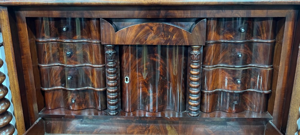 A 19th-century Biedermeier flame mahogany secretaire desk featuring spiralled barley twist columns, a fall-front writing surface, and a fitted interior cabinet. View V