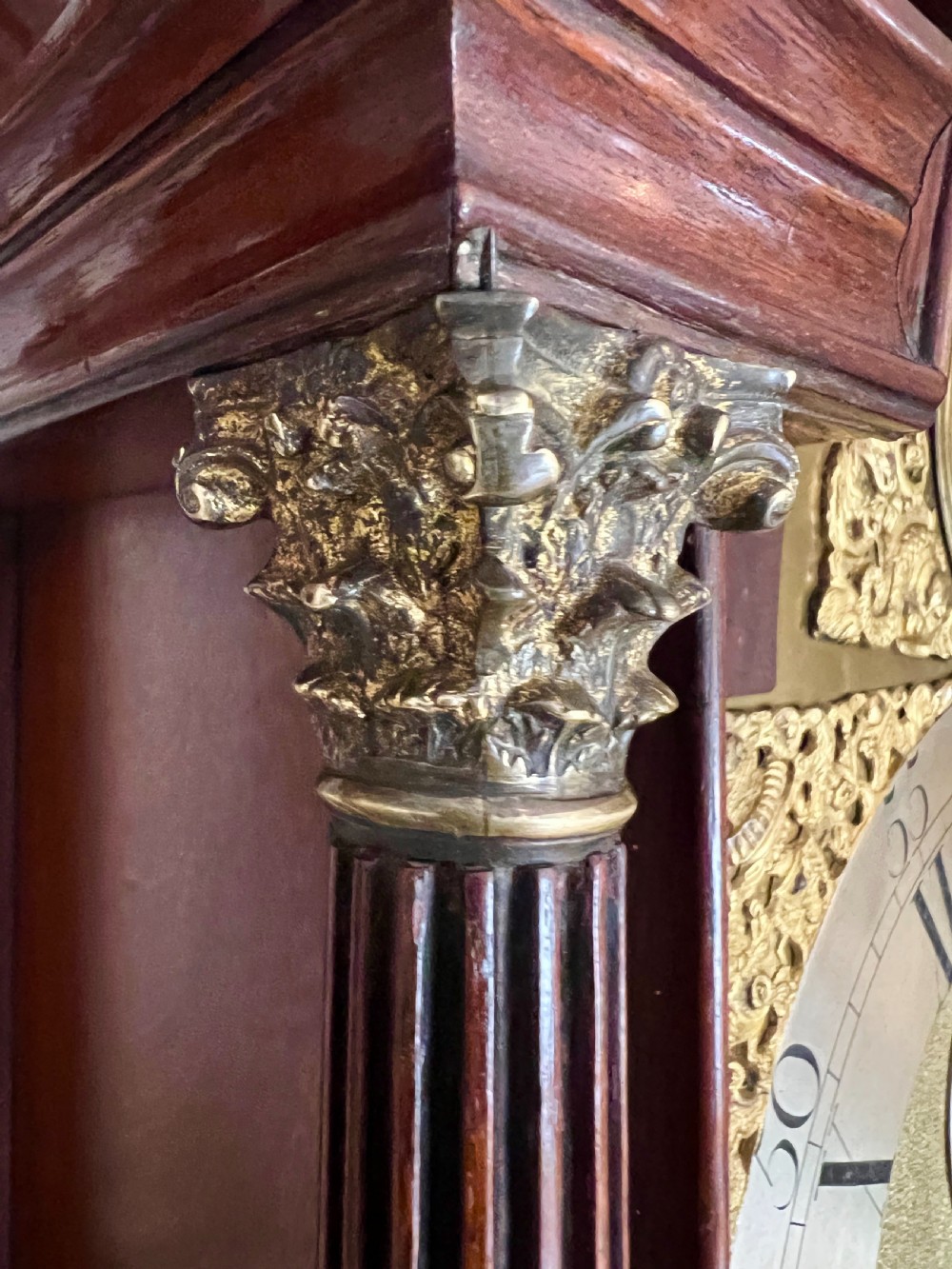 A George III mahogany longcase clock featuring an inlaid trunk door, brass eagle finials, fluted columns, and a brass dial with silvered chapter ring. View V