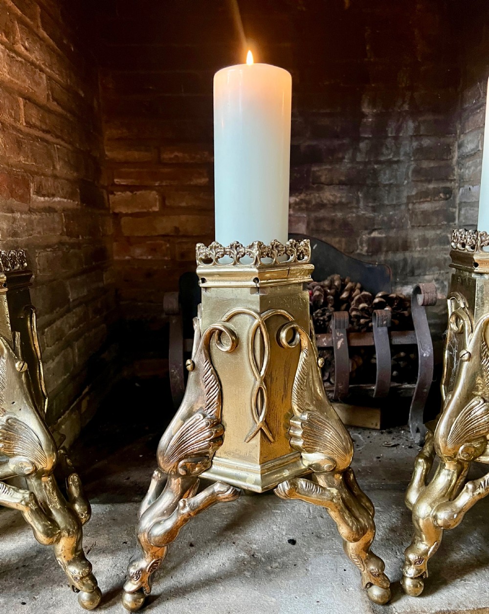 A set of four large ornate cast brass candlesticks featuring pierced crenellated rims, square pedestal bases, and sculpted winged legs ending in hoof feet. View II