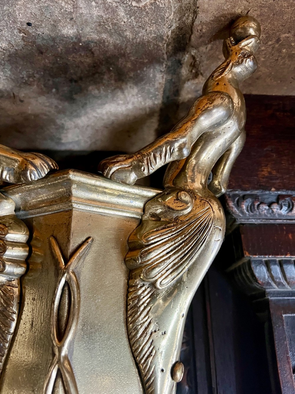 A set of four large ornate cast brass candlesticks featuring pierced crenellated rims, square pedestal bases, and sculpted winged legs ending in hoof feet. View III