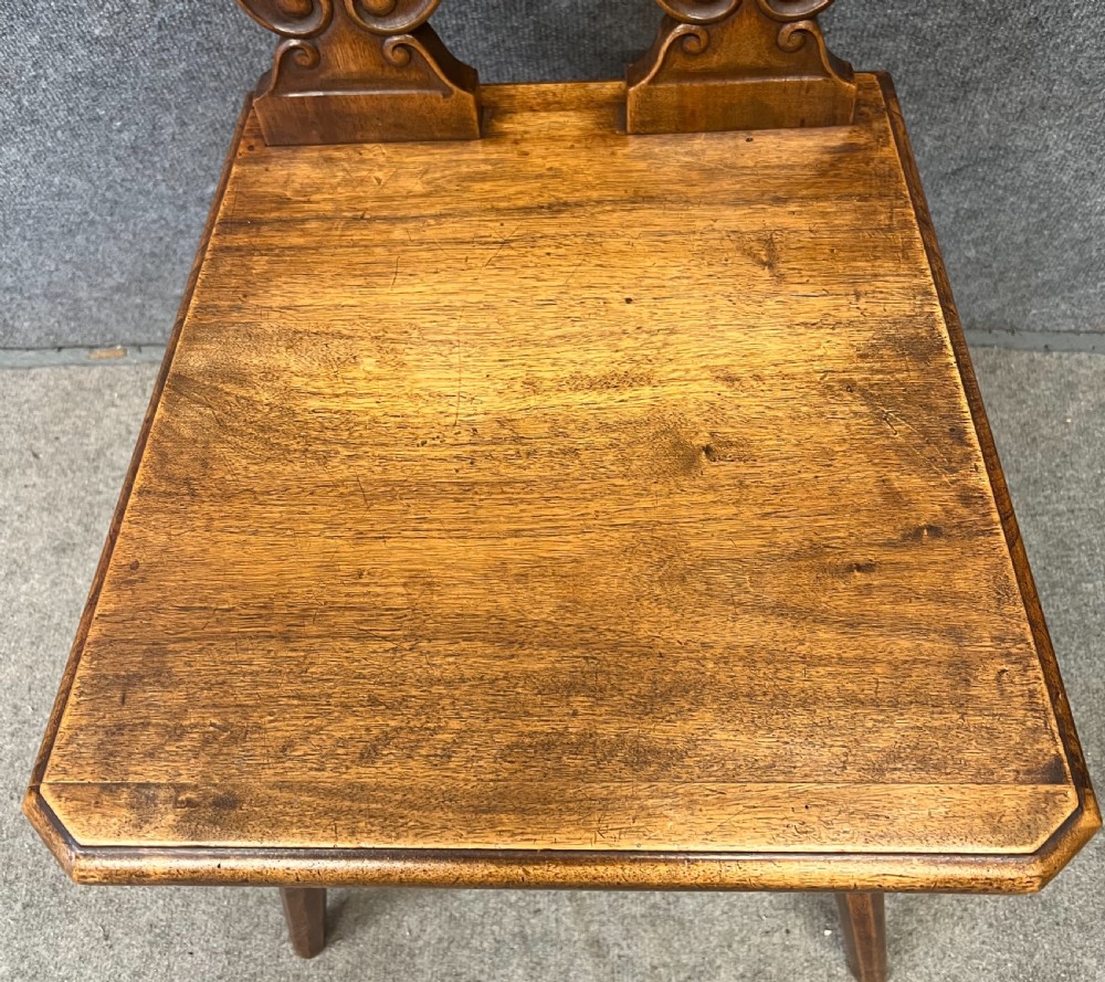 A set of four carved timber Swiss Alpine escabelle chairs featuring detailed scrollwork and heart motifs on the backrests with splayed tapered legs. View V