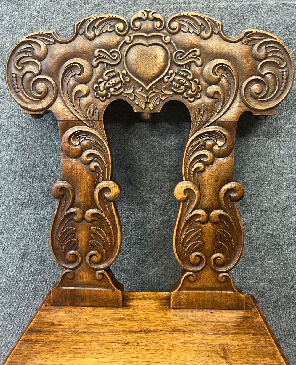 A set of four carved timber Swiss Alpine escabelle chairs featuring detailed scrollwork and heart motifs on the backrests with splayed tapered legs. View VI