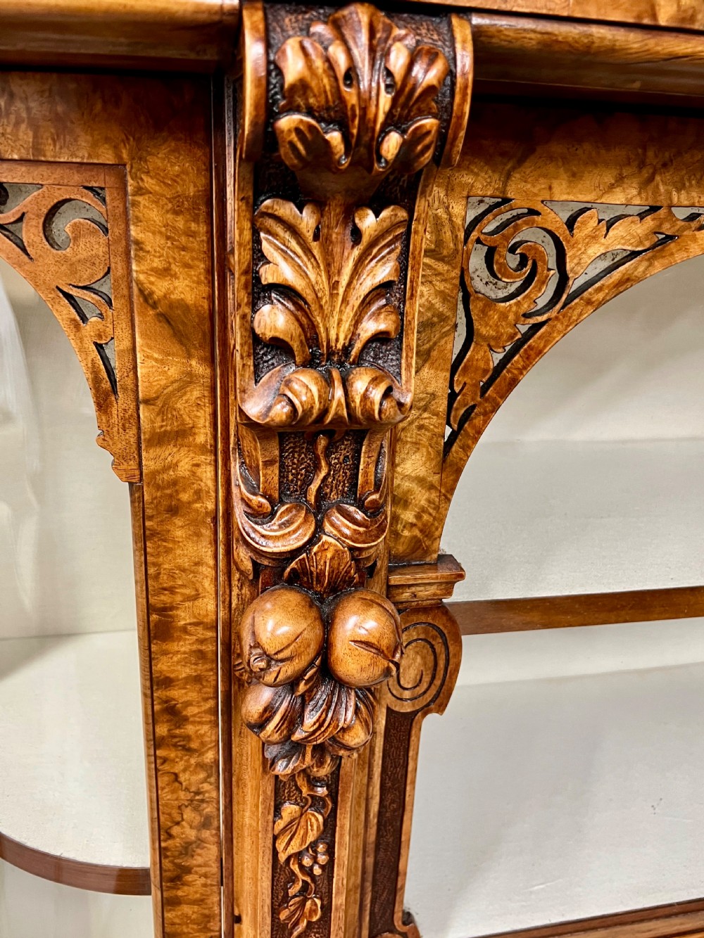 A pair of matching Victorian burr walnut cabinets featuring carved foliate detailing, open central shelving, and curved glass side compartments. View III